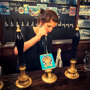 A young woman serves a pint of cask ale