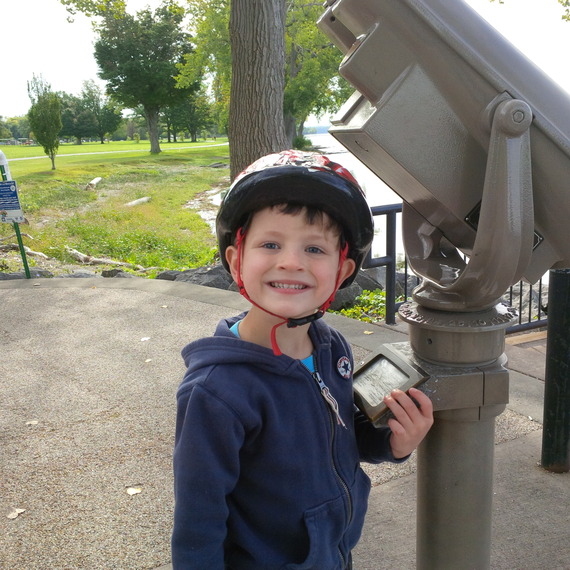 Kate's son wearing a helmet and smiling.