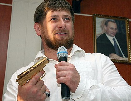 Ramzan Kadyrov poses with his golden gun in front of portrait of Vladimir Putin