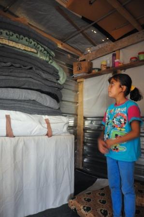 9-year-old Ayat looks at the blankets in her home — a tent in Za'atari Camp.