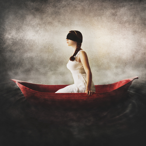 Surreal Fine Art by Jen Kiaba of a blindfolded woman in a white dress sitting in a red boat surrounded by darkness