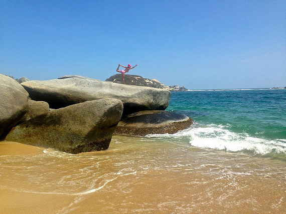 Bow pose on giant boulders Tayrona National Park Colombia