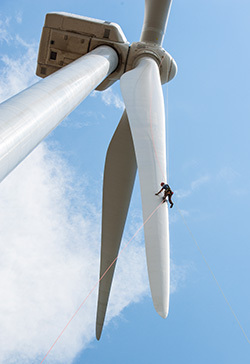 A worker inspects the blades of a wind turbine in Colorado. (Photo by Dennis Schroeder / NREL)